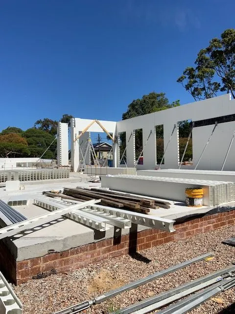 White Dincel wall frames and concrete structure under a blue sky
