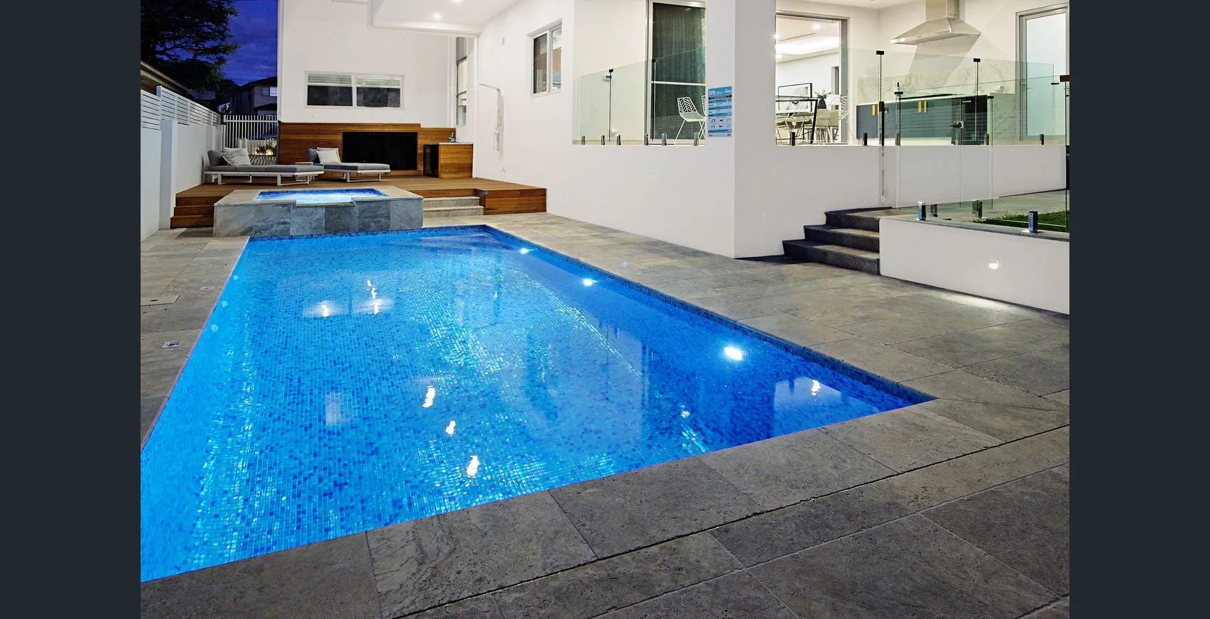 Finished in-ground swimming pool with stone paving and outdoor entertaining area
